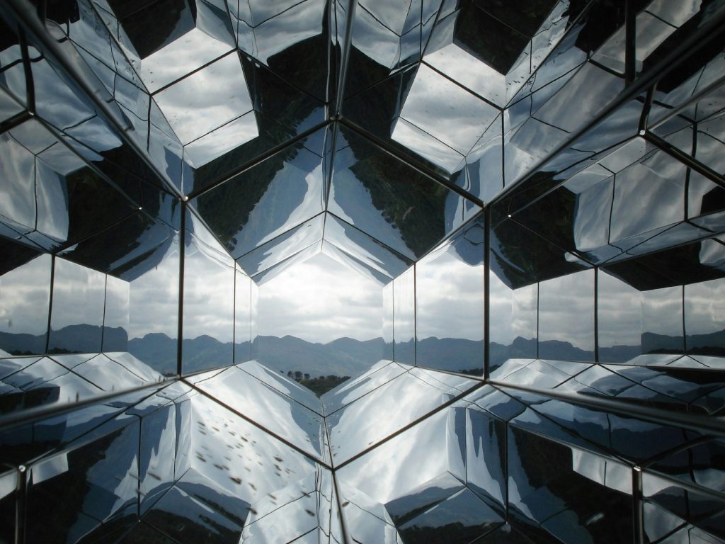 A room filled with mirrors with the reflection of mountains.
