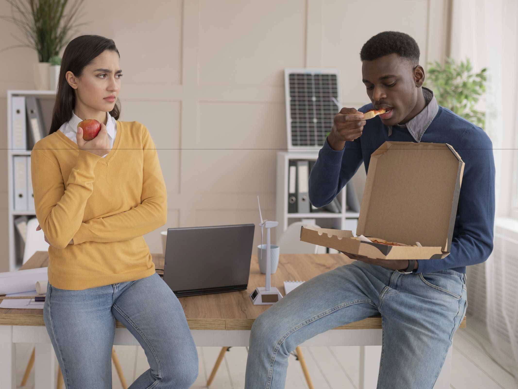 An employee eating pizza and another employee eating an apple